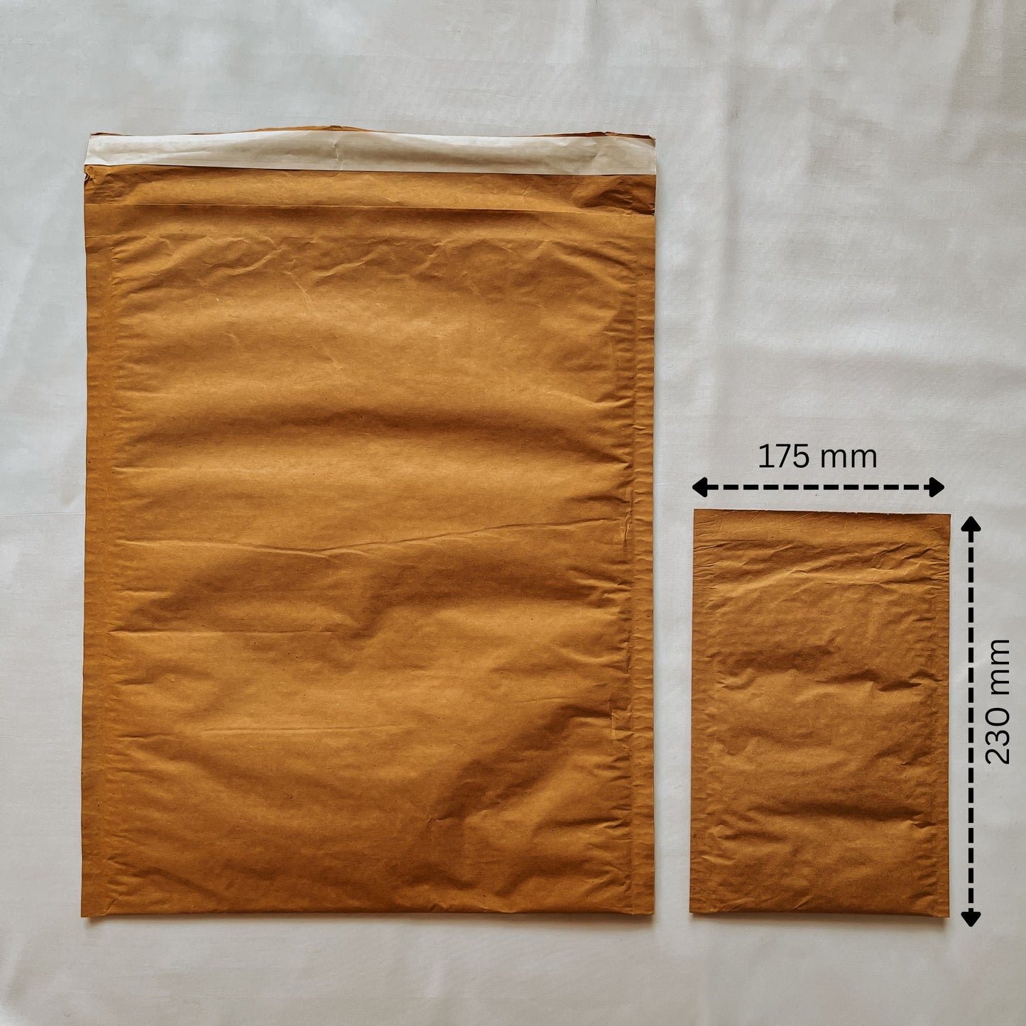 Front view of Jaivik Store EcoArmor shockproof paper mailer (175x230mm) compared to a larger mailer for size reference