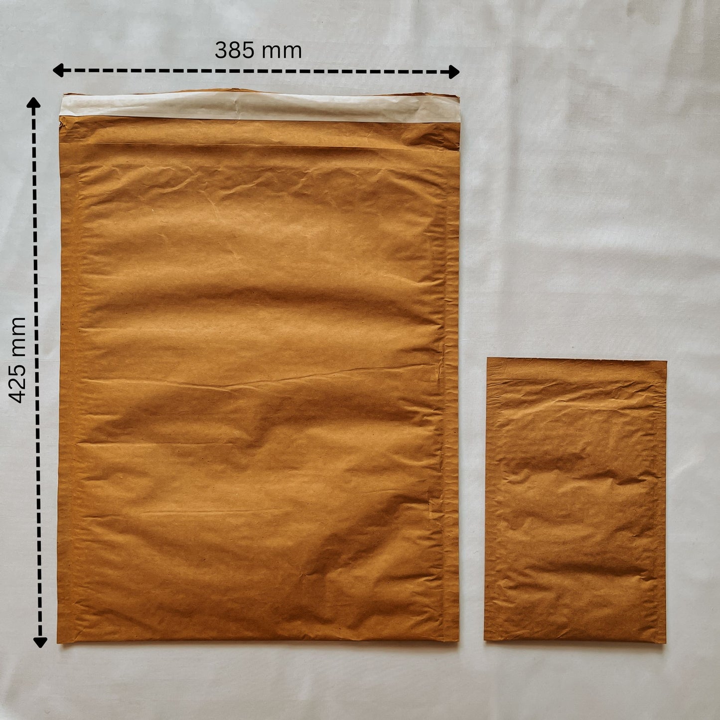 Front view of Jaivik Store EcoArmor shockproof paper mailer (385x425mm) compared to a smaller mailer for size reference